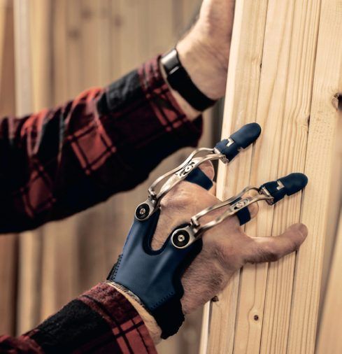 Hand mit Fingerprothesen greift eine Holzlatte