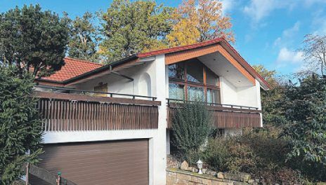 Weisses Architektenhaus mit rotem Satteldach, Balkon und Garage in Liebenau