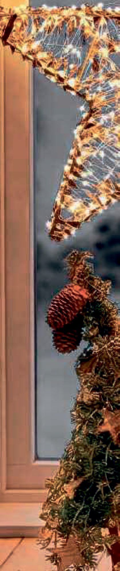 LED-Stern mit Tannenzweigen und Zapfen am Fenster