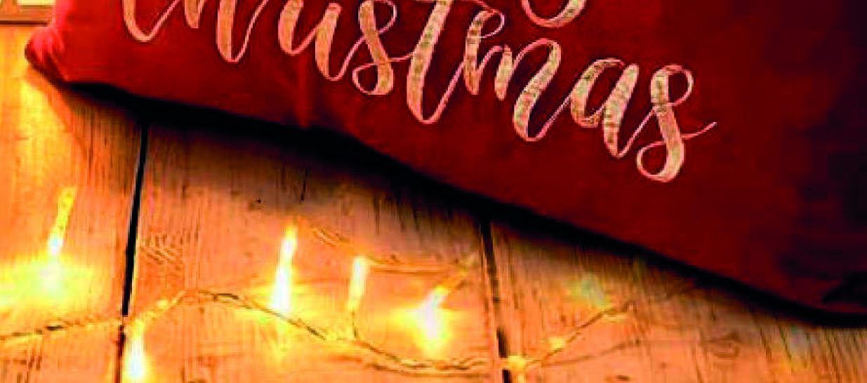 Rotes Weihnachtskissen auf Holzboden mit leuchtender Lichterkette