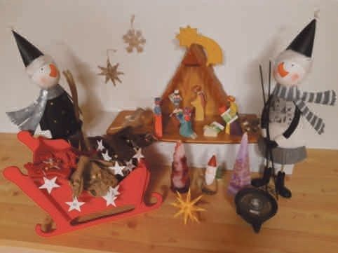 Weihnachtliche Holzdekoration mit Krippe, Schneemann-Figuren, Kerzen und Sternen auf einem Holztisch