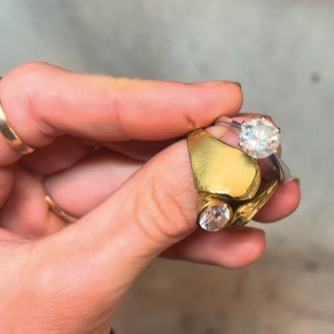 Hand hält zwei goldene Ringe mit großen Brillanten aus eigener Goldschmiede
